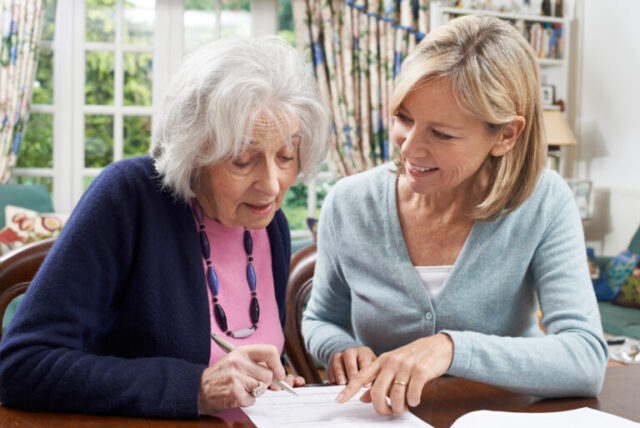 old woman filling up a form with a young woman