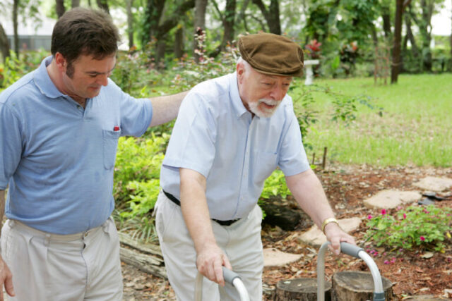 Older man being accompanied by a health care worker